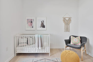 minimalist baby nursery with crib, chair, and wall decor