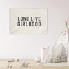child's bedroom with toys scattered on the floor and "long live girlhood" wall flag hung up