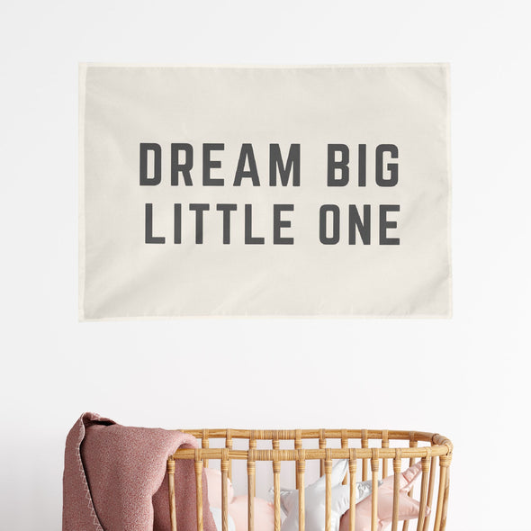 "dream big little one" wall flag hanging above a wicker crib