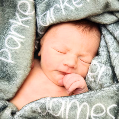 a baby wrapped in a blanket with a name on it