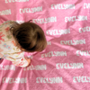 a little girl laying on top of a pink blanket