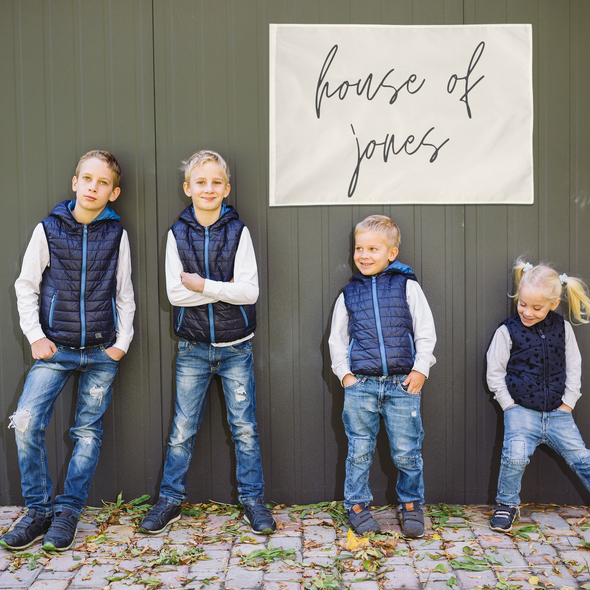 four children standing against an outdoor wall with a decorative wall banner behind them that reads "house of jones"