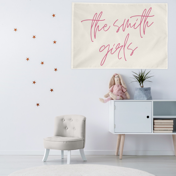 "the smith girls" wall flag hanging above a bookshelf in a children's play room